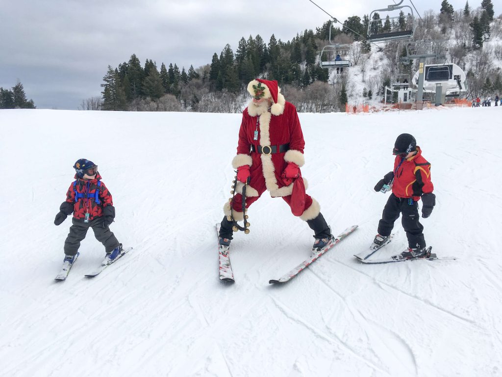 Little kids skiing with santa under a lift