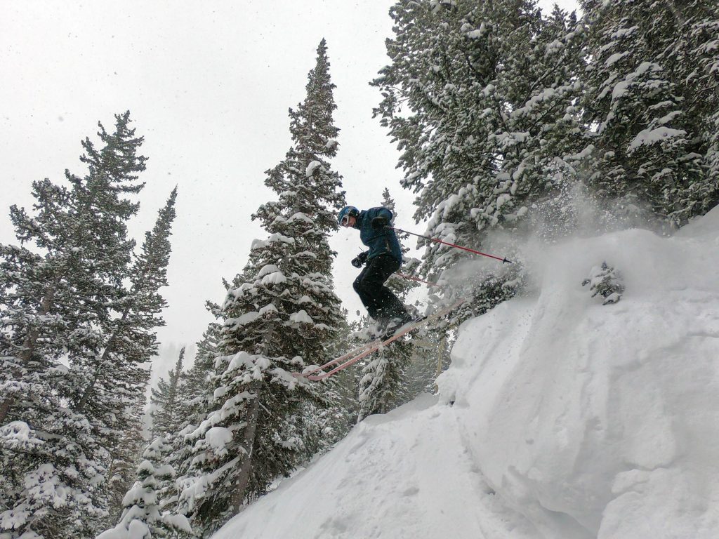 Guy dropping cliff on skis