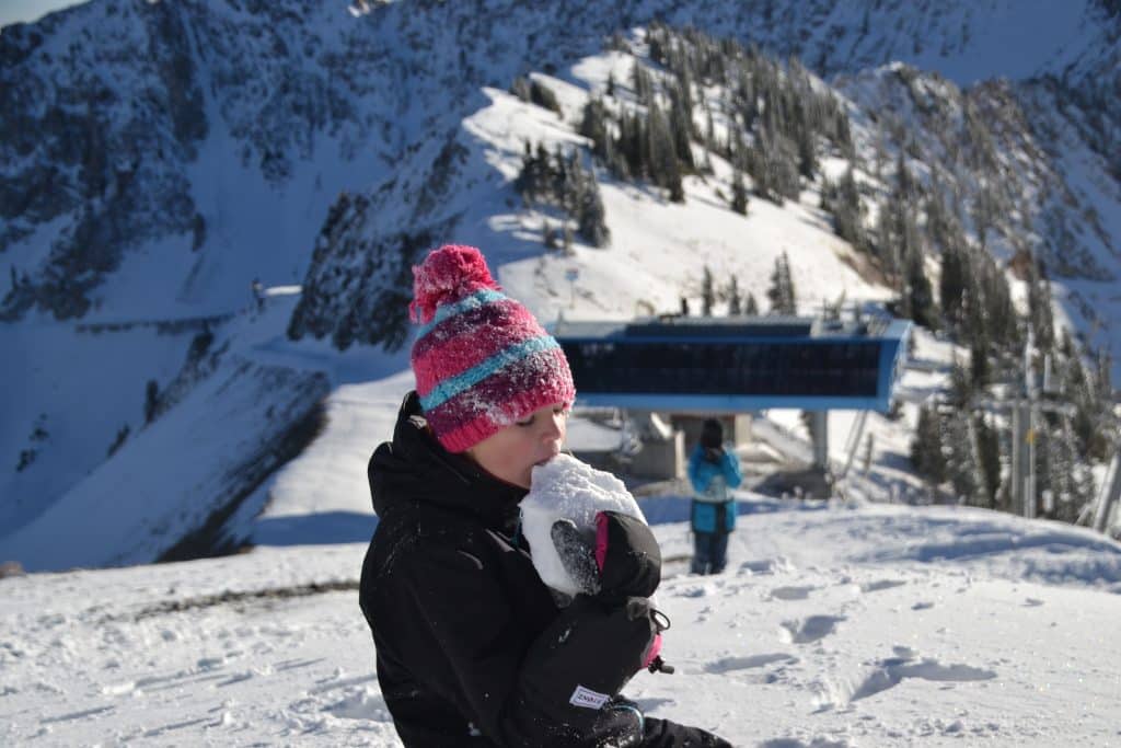 girl eating snow wearing mittens