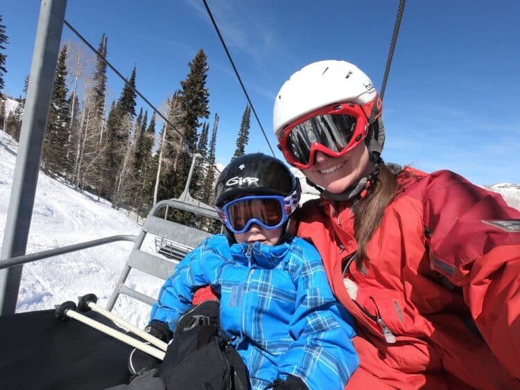 family on chairlift wearing ski goggles