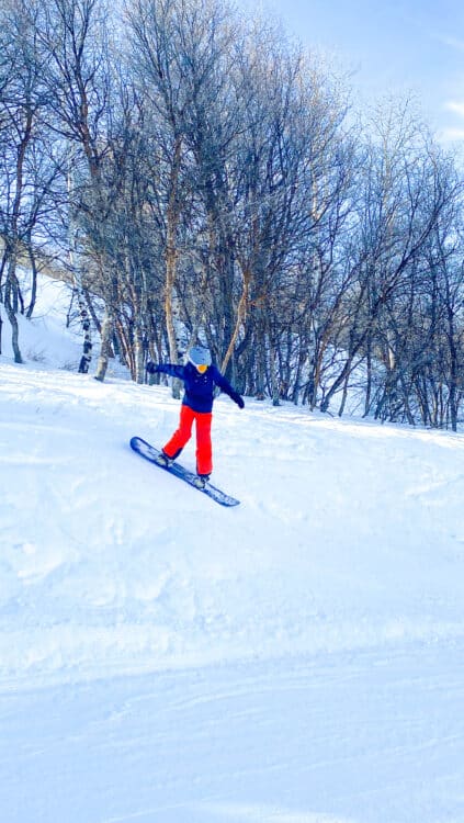 Kid snowboarding wearing mittens