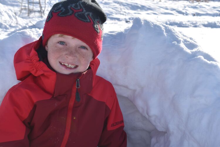 boy sitting in snow wearing a winter hat beanie for kids