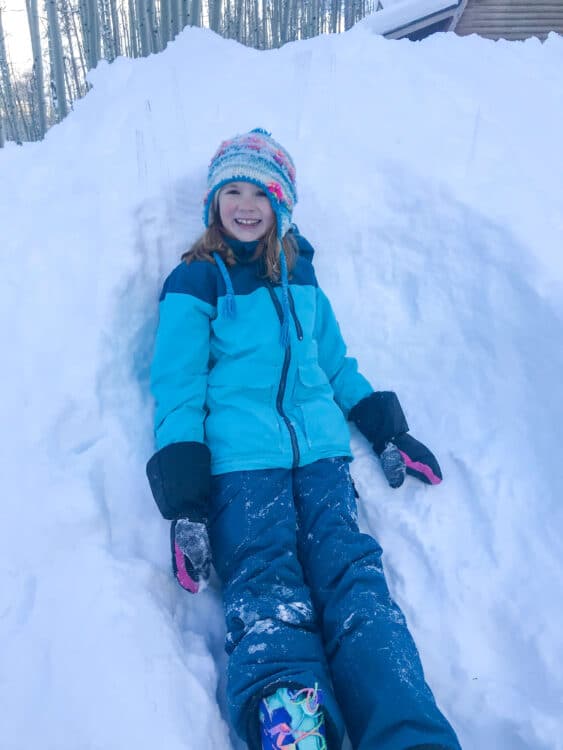 girl in the snow wearig winter clothes and a beanie hat