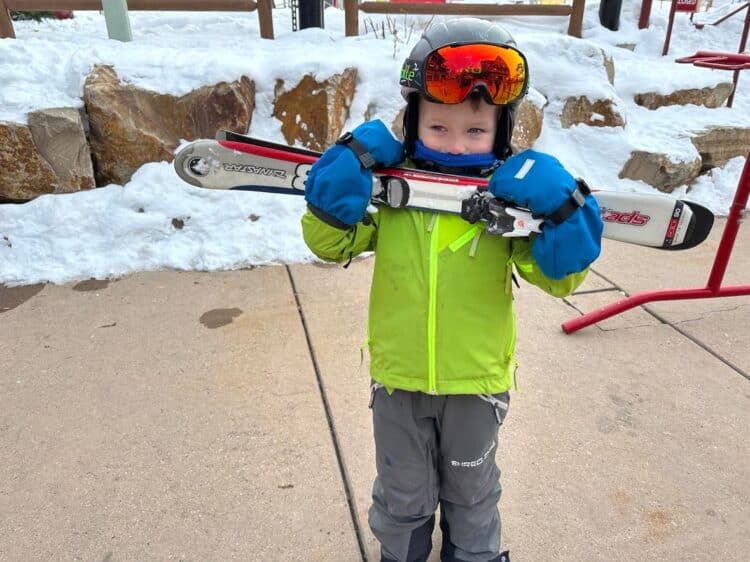 little kid carrying skis