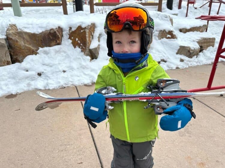 little kid carrying skis