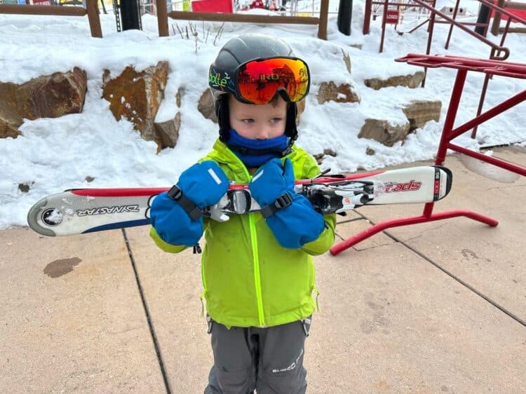 little kid carrying skis