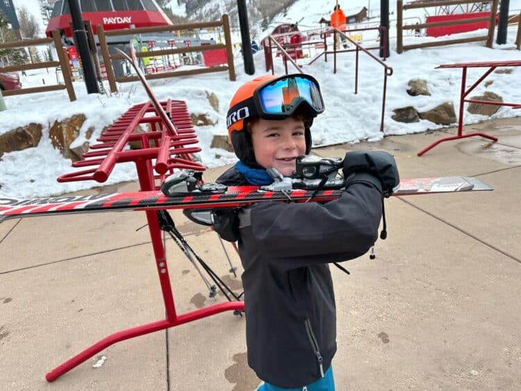 little kid carrying skis