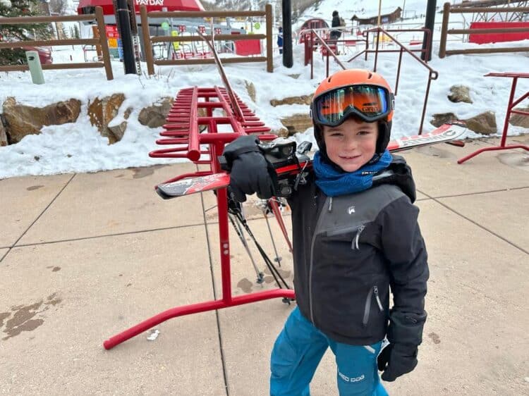 little kid carrying skis